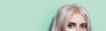 Panoramic half face close-up portrait of blonde girl with blue eyes looking in the camera on studio background of aqua menthe. Royalty Free Stock Photo