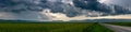 Panoramic image, gathering storm clouds over green agricultural fields