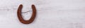 Panoramic image. Rusty horseshoe isolated on bright wooden background