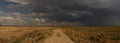 Panoramic image of a storm brewing over country back road and farmland