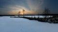 Panoramic image of sunset behind two birches next to a frozen pond in winter Royalty Free Stock Photo