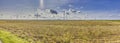 Panoramic image of a wind farm with a coal-fired power plant in the background