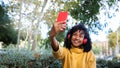 Panoramic image of young African American woman taking a selfie with smartphone in a park. Copy space. Royalty Free Stock Photo