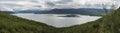 Panoramic landscape of Akkajaure lake at Kungsleden hiking trail, green mountains and birch tree forest in mist and clouds