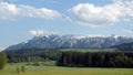 Panoramic landscape with blossoming alpine meadows with green grass and mountains with snow caps at far away