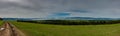 Panoramic landscape, dirt road leading through the green meadow on the top of the mountain Royalty Free Stock Photo
