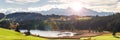 Panoramic landscape with lake aund mountainrange against sky with sun Royalty Free Stock Photo
