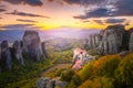 Panoramic landscape of Meteora, Greece at romantic sundown time with real sun and sunset sky. Meteora - incredible sandstone rock Royalty Free Stock Photo