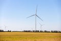 Panoramic landscape view of new white modern wind turbine farm power generation station against clear blue sky and field Royalty Free Stock Photo