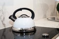 Detail of a white whistling coffee pot on an induction 2.