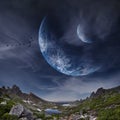 Panoramic mountains and two planets in sky. Fantastic world, birds flying against the background planets of moons. Sunset is