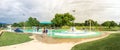 Panoramic multicultural kids and parent playing at splash park under summer stormy weather