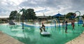 Panoramic multicultural kids and parent playing at splash park under summer stormy weather