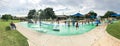 Panoramic multicultural kids and parent playing at splash park under summer stormy weather