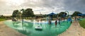 Panoramic multicultural kids and parent playing at splash park under summer stormy weather