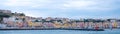 Panoramic photo of the harbour front with pastel coloured houses on the island of Procida Italy, photographed from the water.