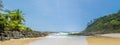 Panoramic photo of Itacarezinho beach, coconut trees, intense vegetation and large stones in encounter with the sea.