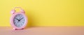 Panoramic photo of pink alarm clock on pink desk yellow wall background with copyspace Royalty Free Stock Photo