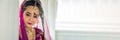 Panoramic picture portrait Asian woman in a margenta Indian tradition sari, she is looking at down at side a white wall for banner