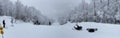 Panoramic picture of Snowboarders sitting on the trail looking down to beautiful panorama valley