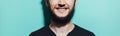 Panoramic portrait of bearded smiling guy on cyan, aqua menthe color background.