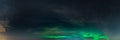 Panoramic real photo of beautiful soft Aurora Borealis - bright green lights on black night sky with some clouds. A lot of real Royalty Free Stock Photo
