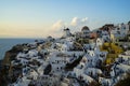 Panoramic scene in evening light of Oia windmill and white building townscape along island mountain facing vast ocean Royalty Free Stock Photo