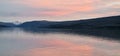 Panoramic shot of a beautiful pink sunset illuminating the sky and reflecting off a lake