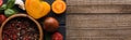 Panoramic shot of black tray with pepper in bowl, chilli pepper, sliced tomatoes and garlic on wooden table. Royalty Free Stock Photo