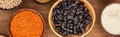 Panoramic shot of bowls with red lentil, black beans, white rice and chickpea on wooden surface. Royalty Free Stock Photo
