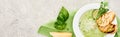 Panoramic shot of delicious creamy green vegetable soup with croutons served on napkin near spinach leaves and cheese. Royalty Free Stock Photo