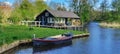 Panoramic shot of a dutch house by the river with a blue boat. Royalty Free Stock Photo