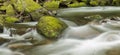 Panoramic shot of flowing river with moss covered rocks