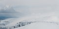 Panoramic shot of the fog surrounding the snowy mountains Royalty Free Stock Photo