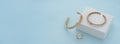 Panoramic shot of golden bracelets and ring on white box on blue background Royalty Free Stock Photo
