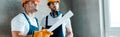 Shot of handsome repairman holding paper roll near coworker Royalty Free Stock Photo