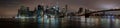 Panoramic shot of the illuminated New York City skyline and the Brooklyn Bridge at the night