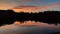 Panoramic shot of a lake surrounded by trees reflecting on the water during a beautiful sunset Royalty Free Stock Photo