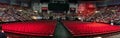 Panoramic shot of people and empty red chairs in the hall of UMass graduation event in Amherst MA
