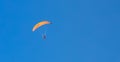 Panoramic shot of a person paragliding under a blue sky