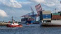 Panoramic shot of the port of Hamburg with a tugboat pushing a container ship out of the harbor Royalty Free Stock Photo