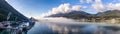 Panoramic shot of port of Juneau and mountains covered with clouds and fog in Gastineau Channel, Alaska. Cruise ship and boats