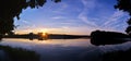 Panoramic shot of the sea surrounded by trees under the sunlight during the sunri