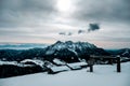 Panoramic shot of a snow covered cabin with a beautiful view of snow capped mountains Royalty Free Stock Photo