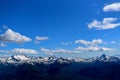 Panoramic shot of snow covered mountain range under cloudy blue skies Royalty Free Stock Photo