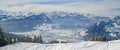 Panoramic shot of snowy mountains under a blue cloudy sky.
