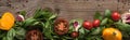 Panoramic shot of spinach, sliced tomatoes, garlic and scattered pepper on wooden table. Royalty Free Stock Photo