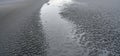 Panoramic shot of textured volcanic ash and sand ground with ripples and cracks.