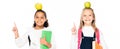 panoramic shot of two cheerful multicultural schoolgirls with apples on heads showing idea gestures isolated on white. Royalty Free Stock Photo