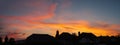 Panoramic silohette of roof tops at sunset. The sky has beauty golden clouds
